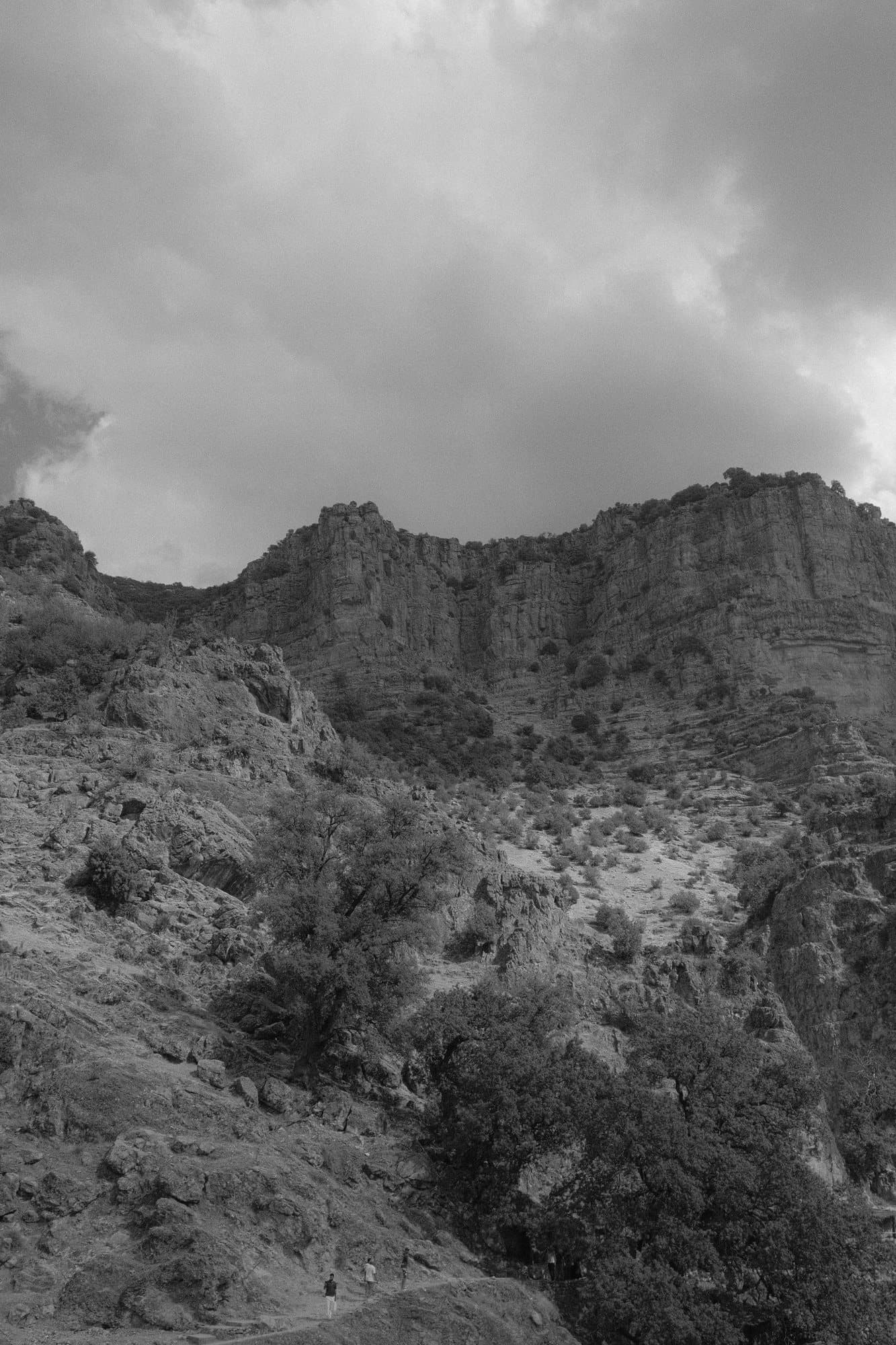 Des falaises de montagne sous un ciel nuageux, en noir et blanc
